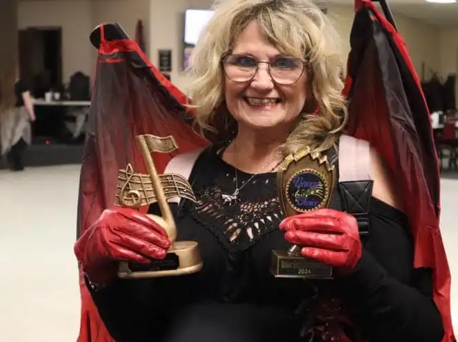 photo of a women dressed into a bat costume holding trophies